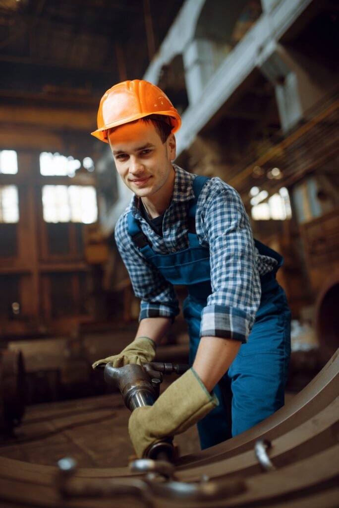 Worker removes scale from metal workpieces